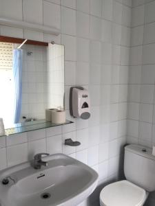 a white bathroom with a sink and a toilet at Hotel Derby in Carballino