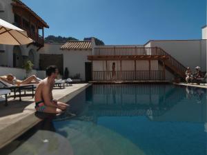 a man sitting on the edge of a swimming pool at Palacio Nazarenas, A Belmond Hotel, Cusco in Cusco