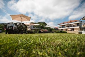 a table and chairs with an umbrella in the grass at Hotel La Bolera in Isla