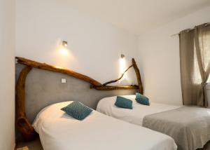 a room with two beds with white sheets and green pillows at Macchie e Fiori in Pianottoli-Caldarello