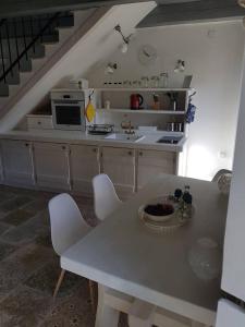uma cozinha com uma mesa branca e cadeiras brancas em Kamena kuća-Stone house em Trebinje