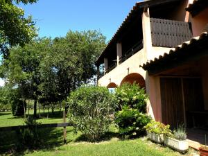 una casa con una valla y algunos arbustos y árboles en Residence de Tourisme Marina Corsa, en Ghisonaccia