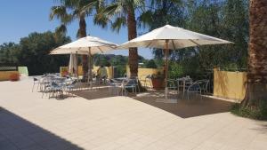 a patio with tables and chairs and umbrellas at Green Garden Club in Briatico