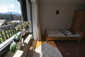 a room with a balcony with a bed and a window at Willa Pod Lasem in Kościelisko