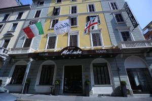 a yellow building with flags in front of it at Mokinba Hotels Baviera in Milan