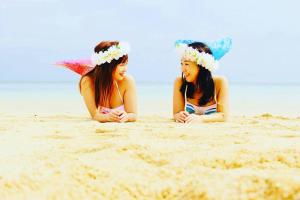 dos mujeres tumbadas en la arena en la playa en 宮古島サイクリストの宿 en Isla Miyako