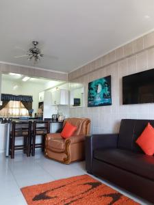 a living room with a couch and a kitchen at Beach frond apartment in Amanzimtoti