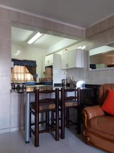 cocina con barra con sillas y sofá en Beach frond apartment, en Amanzimtoti
