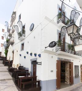 un edificio blanco con bancos de madera delante en La Sepia Boba (Adults only) en Peñíscola