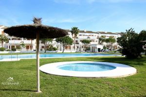 an umbrella in the grass next to a swimming pool at Residencial Carrajolilla in Chiclana de la Frontera