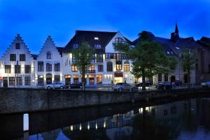 a large building with a boat docked in front of it at Golden Tulip Hotel de’ Medici in Bruges