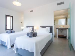 2 Betten in einem weißen Zimmer mit Spiegel in der Unterkunft Villa Can Paulo in Santanyi