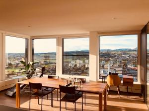 uma sala de jantar com mesa e cadeiras e janelas grandes em Park Tower City View Apartments em Zug