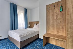Appartis - Hotel am Stadtpark في شيندلفينجن: غرفة نوم بسرير وجدار خشبي
