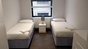 ロンドンにあるAccess Tower Hillのベッド2台と窓が備わる小さな客室です。