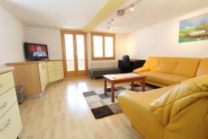 ein Wohnzimmer mit einem gelben Sofa und einem Tisch in der Unterkunft Hotel Alpina Dependance vom Hotel Desiree in Grächen