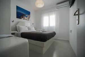 a white bedroom with a bed and a window at Corrado Caldera Apartments in Fira
