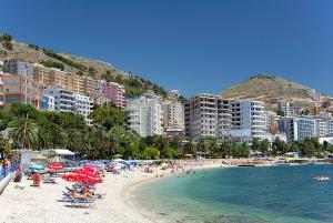 una playa con sombrillas y gente en el agua en Margaritas Apartments en Sarandë