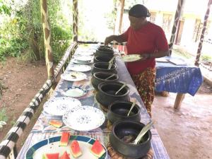 a woman standing at a long table with plates of food at Machame Nkweshoo Cultural Tourism in Machame +41 photos
