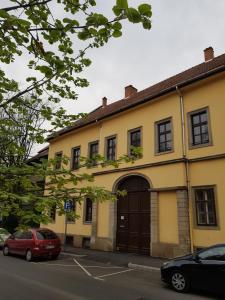 a yellow building with a brown door on a street at Cozy Loft Apartman in Eger