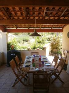 - une table en bois avec des chaises sur la terrasse dans l'établissement La Gravelière, à Rémuzat