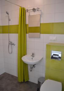 a bathroom with a sink and a green shower curtain at Morza Szum in Dziwnów +45 photos