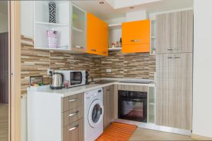 a kitchen with orange cabinets and a washer and dryer at Family Apartment London in Verona