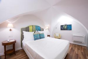um quarto com uma grande cama branca e uma cadeira em DieciSedici em Amalfi
