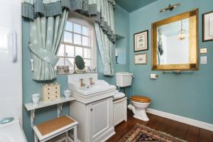 a bathroom with a sink and a toilet and a mirror at Newton Cottage in Porthcawl