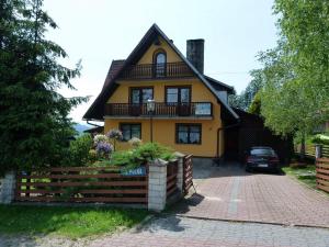 żółty dom z płotem przed nim w obiekcie Noclegi Barbara w Czorsztynie