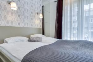 a bedroom with a large bed with a window at Elite Apartments Kwartal Kamienic in Gdańsk