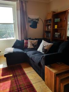 a living room with a black couch and a window at The Herring Queen in Eyemouth +16 photos