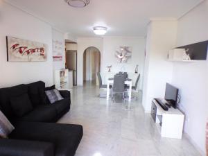 ein Wohnzimmer mit einem schwarzen Sofa und einem Tisch in der Unterkunft Villamartin Violetas holiday home in Villamartin