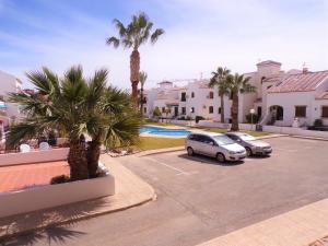 two cars parked in a parking lot with palm trees at Villamartin Violetas holiday home in Villamartin