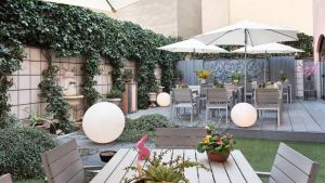 eine Terrasse mit Tischen, Stühlen und einem Sonnenschirm in der Unterkunft Hotel Lombardia in Mailand