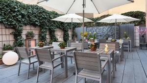 un patio con mesas, sillas y sombrillas en Hotel Lombardia, en Milán