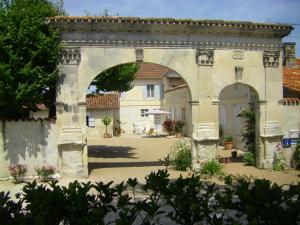 un arco que conduce a un edificio con patio en Chambre d'Hôtes Clos des Pierres Blanches, en Brie-sous-Archiac