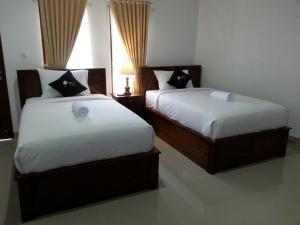 twee bedden in een hotelkamer met rokken bij Ega Homestay in Nusa Penida