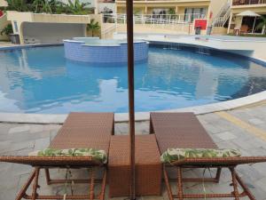 - deux chaises assises à côté de la piscine dans l'établissement Solar Água Pipa - Apto 115, à Pipa