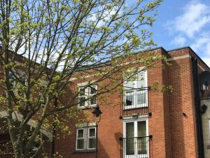 a red brick building with white windows and a tree at Godwin Court 21 in Swindon