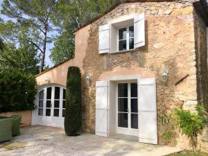 uma casa de pedra com portas e janelas brancas em Le Champmazet em La Roquette-sur-Siagne