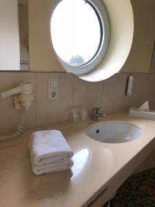 a bathroom with a sink and a round window at Nordseehotel Benser Hof am Hafen in Bensersiel