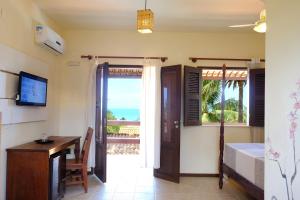 a bedroom with a bed and a desk and a window at Hotel e Pousada La Dolce Vita in Canoa Quebrada