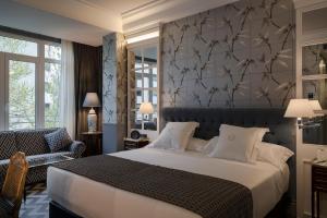 a bedroom with a large bed and a chair at Relais & Châteaux Heritage Hotel in Madrid