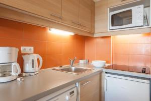 a kitchen with a sink and a microwave at Résidence Pierre & Vacances Les Gémeaux in Belle Plagne