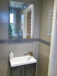 een badkamer met een wastafel en een spiegel bij The Norfolk Townhouse - Stunning 5BDR Home in Londen