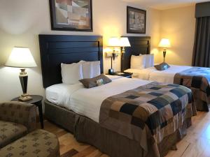 um quarto de hotel com duas camas e uma cadeira em Wingate by Wyndham LaGrange em La Grange