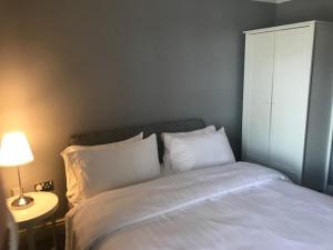 Una cama con sábanas blancas y almohadas en un dormitorio en Cheshire Cat en Nantwich