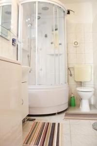 a white bathroom with a shower and a toilet at Apartments Tragurion in Trogir