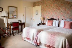 a bedroom with two beds and a desk with a chair at Hazelwood Lodge in Ballyvaughan